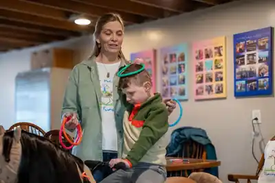 Child participating in a colorful ring activity beside the MiraColt with Dawn Miller